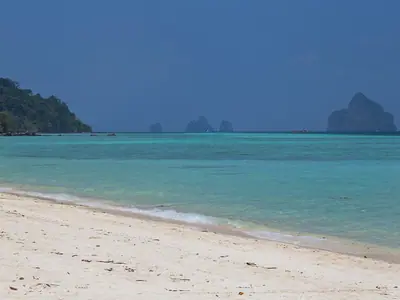 Beach and clear water on Ko Kradan with limestone islets in the distance