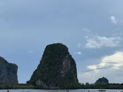 Limestone rock rising from the water at Ao Pak Meng with long-tail boats in Hat Chao Mai National Park