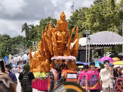 A parade float of golden carved wax figures passing spectators at the Ubon Ratchathani Candle Festival, Buntharik district (July 2026)