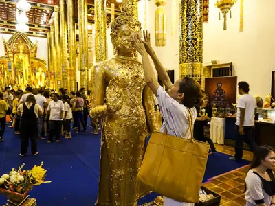 Buddhist followers make merit before a golden Buddha statue at Wat Chedi Luang in Chiang Mai on Visakha Bucha