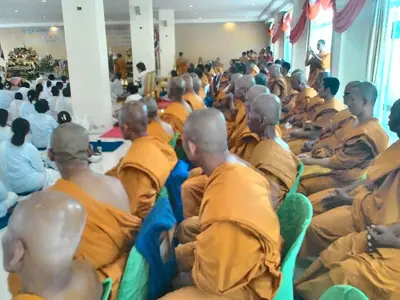 Monks and white-clad laypeople seated in a hall for Visakha Bucha day at Wat Pa Pavanaram