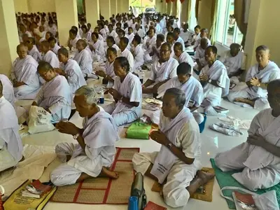 Rows of white-clad laypeople praying in a hall on Visakha Bucha day at Wat Pa Pavanaram