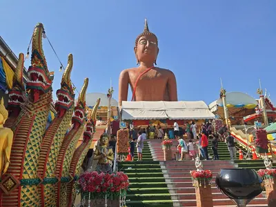 Great Buddha statue above a naga-lined staircase at Wat Bang Phra (Luang Phor Somwang) with visitors
