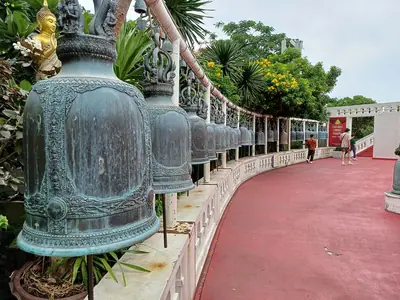 A row of large bronze bells along the red-paved spiral path up the Golden Mount