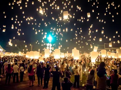 Crowd gathered under thousands of floating sky lanterns at Yi Peng in Chiang Mai