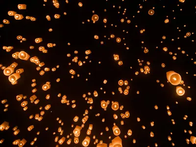 Dense field of sky lanterns rising into the night during Yi Peng in Chiang Mai