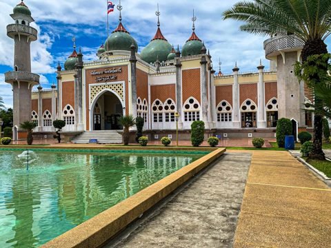 Moskee met groene koepels en minaretten die weerspiegeld worden in een vijver in Pattani, Zuid-Thailand