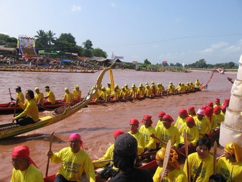 Langboten met roeiers in gele shirts tijdens een race op de Nan-rivier, met toeschouwers aan de oever
