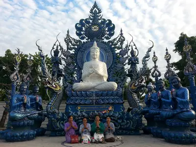 White Buddha statue among blue sculptures, Wat Rong Suea Ten