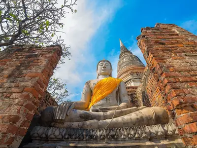Boeddhabeeld met oranje sjerp tussen bakstenen muren, Wat Yai Chai Mongkhon