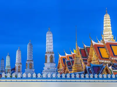 Rij kleurrijke porseleinen prangs onder een diepblauwe lucht, Wat Phra Kaew