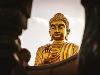 Golden Buddha statue seen through foliage, Wat Samphran
