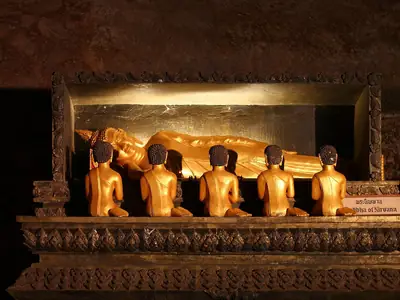 Row of golden Buddhas lit in the cave, Wat Suwan Khuha (Phang Nga)